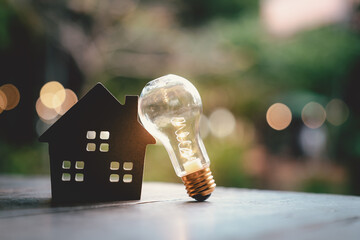Wood house with Light bulb on the table, a symbol for construction, Creative light bulb idea, power...