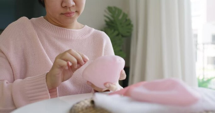Close-up hand asia woman help make craft pink single fill up bra cup insert for post mastectomy prosthesis surgery MRM at home. Relief work service support give hope to tumor patient medical issue.