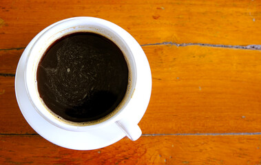 white coffee cup with a black coffee on a wooden table.