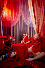 Young teenager girl during a stylized theatrical circus photo shoot in a beautiful red location....
