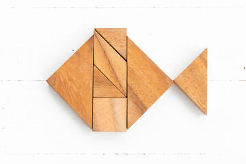 Wood tangram puzzle in fish shape on white wood background