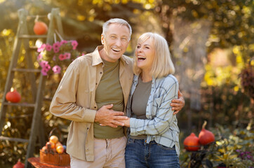 Naklejka na ściany i meble Family lifestyle concept. Happy senior couple walking and laughing at garden outdoors, enjoying time together