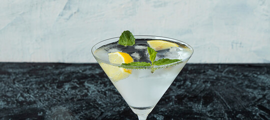 banner with martini glass with cold drink on black and white background. refreshing cocktail on hot day made of ice, lemon and mint.