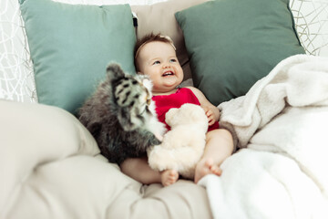 Lovely smiling little girl lies on the bed with plush toys. Childhood