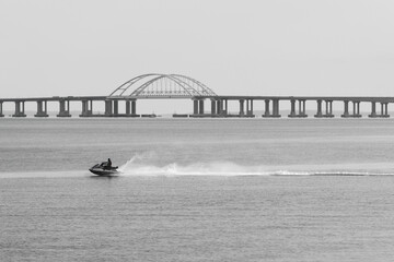 a man on a jet ski rides against the background of the Crimean bridge