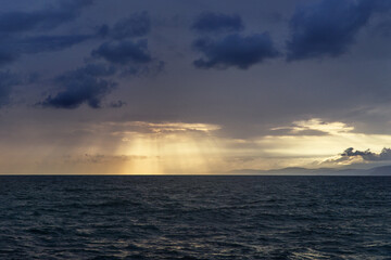 Naklejka na ściany i meble the setting sun shines through the clouds over the Black Sea