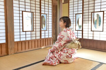 古民家の和室でくつろぐ浴衣を着た若い女性