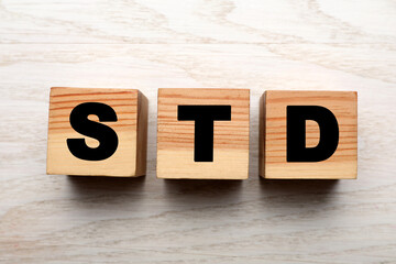 Abbreviation STD made with cubes on white wooden table, flat lay