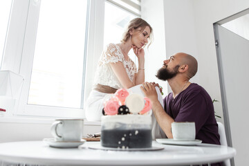 Loving couple in love celebrate their anniversary in the kitchen with cake. Romantic love concept
