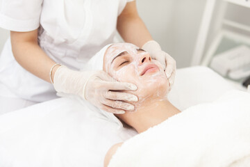 Obraz na płótnie Canvas Facial skin care procedures. Beautician makes massage procedure with beauty woman's face in cosmetic clinic