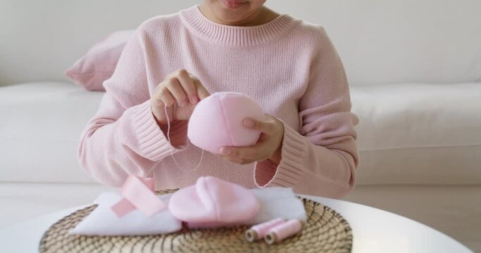Close-up hand asia woman help make craft pink single fill up bra cup insert for post mastectomy prosthesis surgery MRM at home. Relief work service support give hope to tumor patient medical issue.
