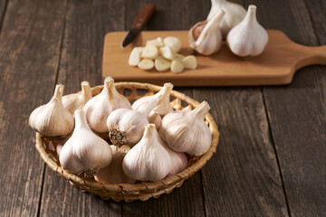 whole garlic bulbs in a basket on a wooden table.