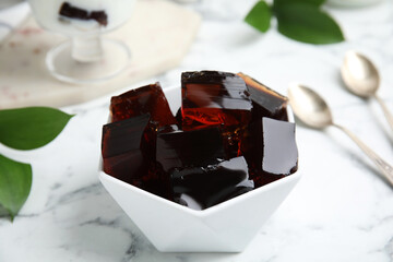 Delicious grass jelly cubes on white marble table, closeup