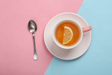 Cup of black aromatic tea with lemon on blue-pink pastel background. Top view. Flat lay