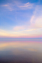 Beautiful sunset on sea, pastel colors and reflections on water, calm nature landscape with colorful clouds