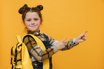 Closeup portrait of nice cute attractive happy glad schoolgirl wear yellow backpack pointing two...