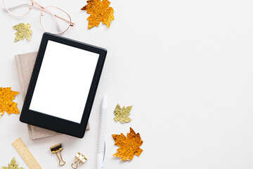 Cozy autumn workspace. Home office desk table with ebook mockup, maple leaves and glasses on white. Flat lay, top view, copy space. Hygge style