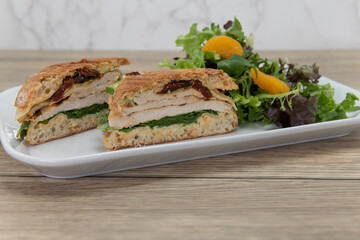 Chicken panini sandwich showing layers of meat and ingredients served with a salad on a plate