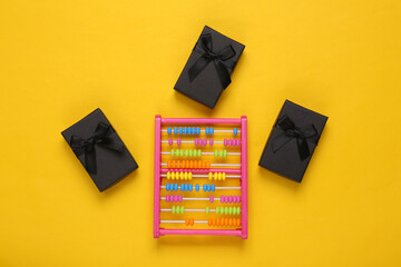 Childrens toy abacus and gift boxes on yellow background. Top view