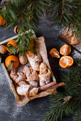 Fototapeta na wymiar Christmas bagels with nuts. croissants. Tangerines and pastries on a gray background. New Year's atmosphere. Hazelnuts and walnuts. Bagels with cinnamon in a box.