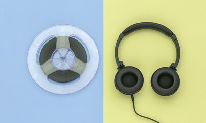Stereo headphones and magnetic audio reel on yellow blue pastel background. Top view