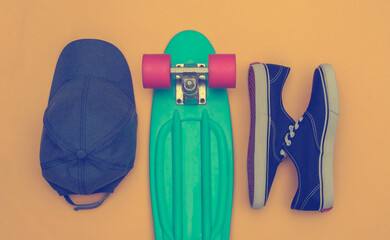 Flat lay composition of mini cruiser board, sneakers and cap on yellow background. Youth, hipster...