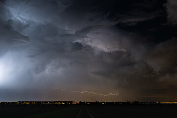 Storm cloud at night with orange colored horizontal lightning discharge