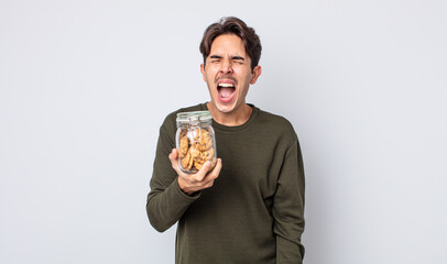 young hispanic man shouting aggressively, looking very angry. cookies concept