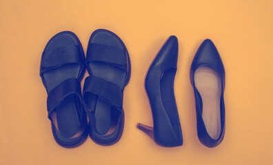 Women's leather shoes with heels and sandals on a yellow background. Top view