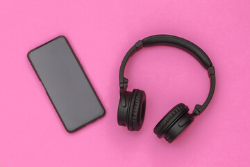 Wireless stereo headphones and smartphone on pink background. Top view