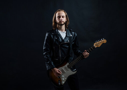 bearded rock musician playing electric guitar in leather jacket, guitarist
