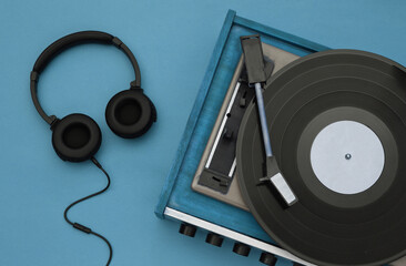 Retro vinyl player and stereo headphones on blue background. Top view. Flat lay