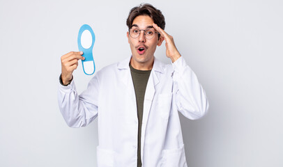 young hispanic man looking happy, astonished and surprised. chiropodist concept - obrazy, fototapety, plakaty