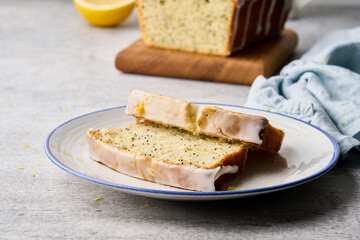 Delicious white icing lemon fruitcake with poppy seeds and orange peel served on plate. Healthy and vegetarian homemade sweet bakery. Side view, closeup, horizontal