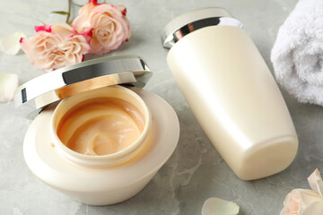 Hair care cosmetic products and flowers on light grey marble table