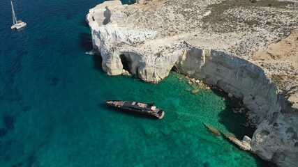 Aerial drone photo of luxury yacht anchored near famous white chalk volcanic bay of Sarakiniko, Milos island, Cyclades, Greece