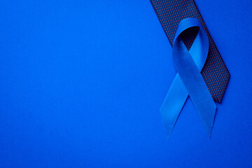 Cancer awareness blue. Blue ribbon, fashion tie isolated on deep blue background. Awareness...
