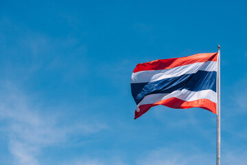 Waving Thai flag of Kingdom of Thailand with blue sky background and copy space.