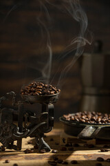 Coffee beans with smoke or steam on vintage scales and frying pen. Wooden dark brown background. Hot grains with beautiful light. 