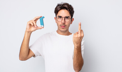 young hispanic man feeling angry, annoyed, rebellious and aggressive. asthma concept