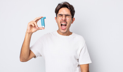 young hispanic man shouting aggressively, looking very angry. asthma concept
