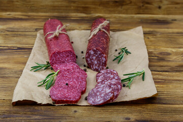 Salami sausages on craft paper on a wooden table