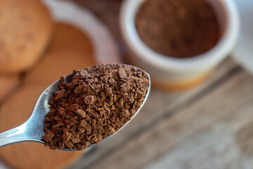 Close-up of a metal spoon with instant coffee, with an unfocused background. Soluble coffee concept.
