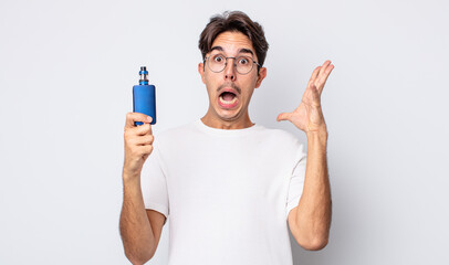 young hispanic man screaming with hands up in the air. smoke vaporizer concept
