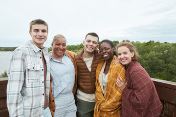 Waist up length portrait of diverse group of young friends taking selfie at viewpoint during hike