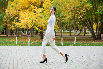 Young beautiful brunette girl walking in autumn park