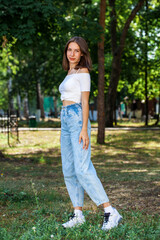 Young beautiful girl in blue jeans posing in a summer park