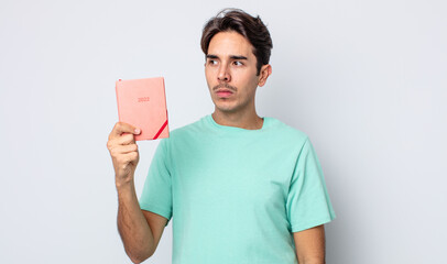 young hispanic man feeling sad, upset or angry and looking to the side. 2022 planner concept