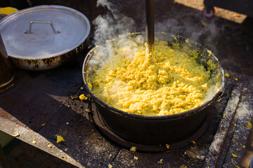 cauldron with polenta while cooking with wooden ladle