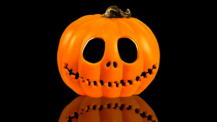 Isolated Pumpkin head Jack-o'-lantern close-up on black background with reflection